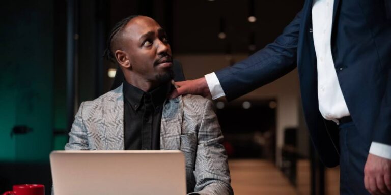 Business professional with laptop receiving guidance from accountability coach during workplace coaching session