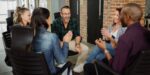 Business owners seated in a circle discussing challenges and successes during a session focused on the benefits of group coaching