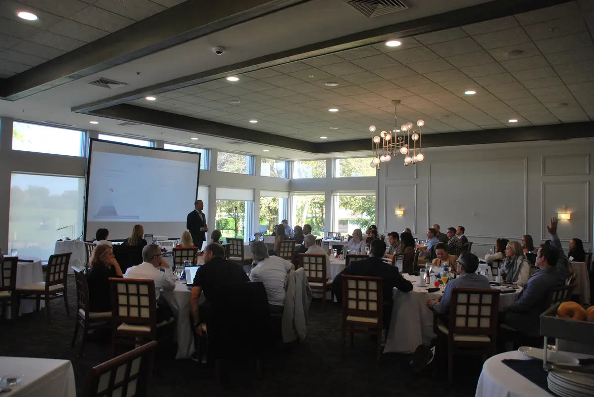 Business coach presenting to group of business owners during live workshop seminar