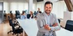 Confident business leader standing in a bright office, representing strategic planning for business growth goals and sustainable company success.