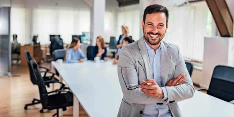 Confident business leader standing in a bright office, representing strategic planning for business growth goals and sustainable company success.