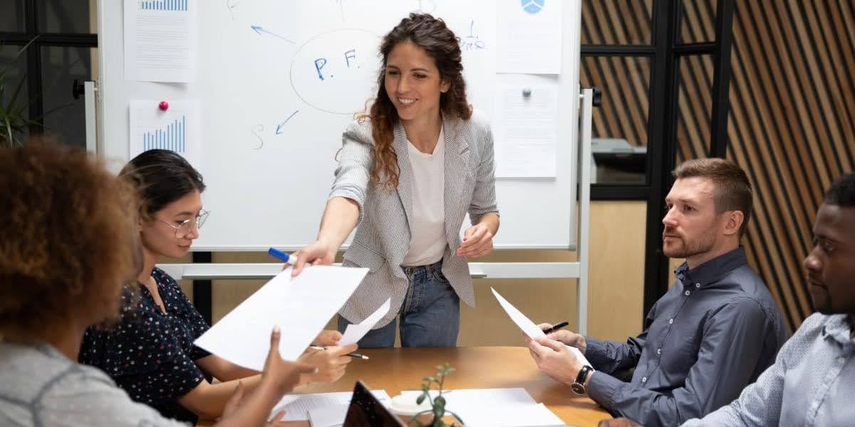 Team meeting with a leader distributing papers and guiding discussion, demonstrating effective delegation in leadership