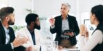 A professional woman demonstrating executive leadership while presenting ideas to an engaged team during a business meeting