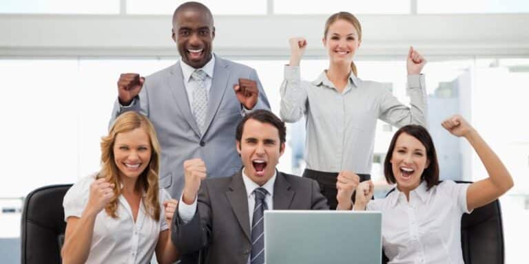 Business team celebrating success after achieving clear goals vs objectives alignment in workplace strategy