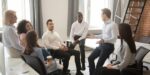 Business coach leading a discussion with team members seated in a circle, illustrating group coaching vs individual coaching differences