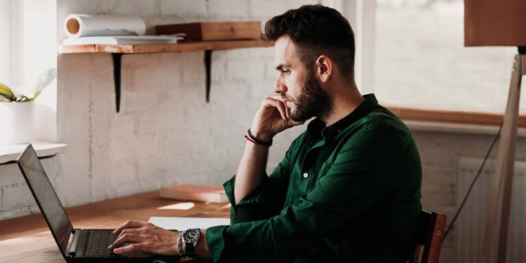 Business leader working at laptop reflecting on growth mindset vs fixed mindset in leadership and company success