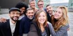Smiling business professionals posing for a group photo outdoors, representing the results of successful leadership team development