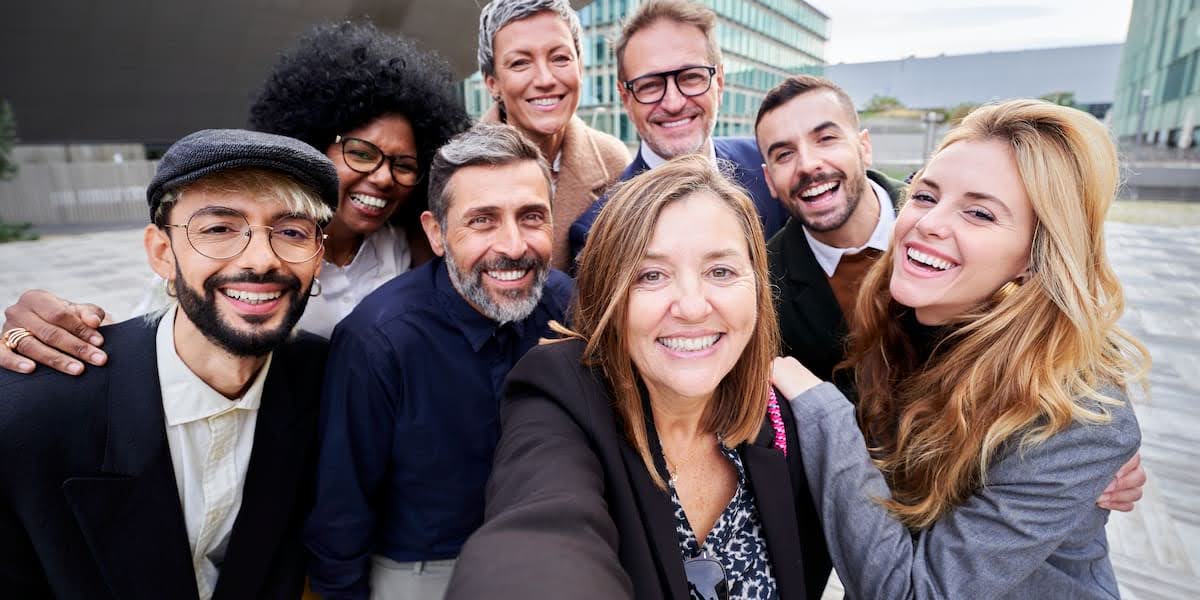 Smiling business professionals posing for a group photo outdoors, representing the results of successful leadership team development