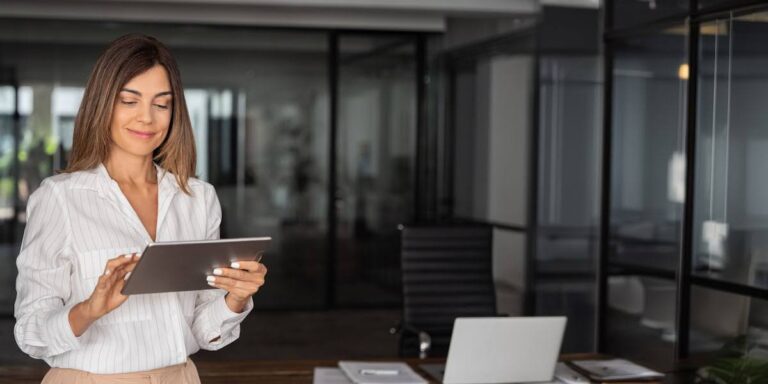 Woman entrepreneur using a tablet in a modern office, illustrating productivity tips for entrepreneurs like time-blocking and delegation.