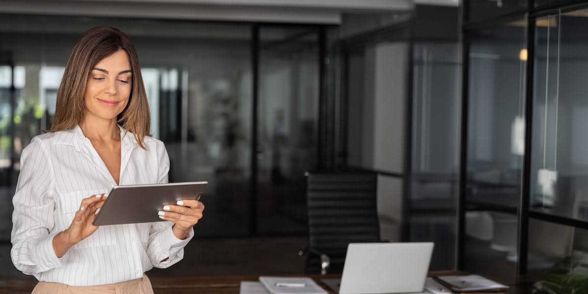 Woman entrepreneur using a tablet in a modern office, illustrating productivity tips for entrepreneurs like time-blocking and delegation.