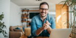 Smiling business professional practicing remote leadership skills while working from home office with laptop and modern decor