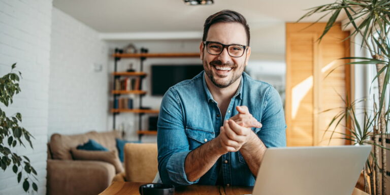 Smiling business professional practicing remote leadership skills while working from home office with laptop and modern decor