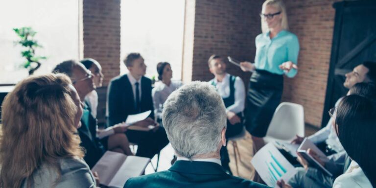 Group of professionals attending a small business leadership training session led by a woman in business attire, discussing strategy and teamwork